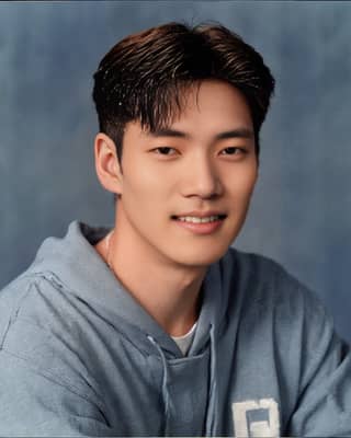 Homme asiatique souriant dans un sweat à capuche bleu et gris posant pour une photo.