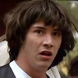 Conspiracy Keanu dengan rambut panjang dan kemeja putih, pria dalam jas dan dasi dengan ekspresi terkejut di wajahnya.