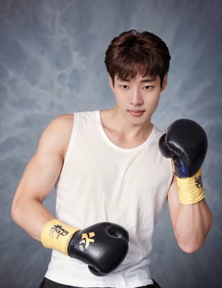 Koreanischer Boxer in einem weißen Tanktop und schwarzen Boxhandschuhen.