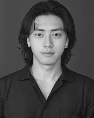 Long hair, black and white shirt. Actor known for role in the Korean drama 'The Man Who Knew Infinity'.