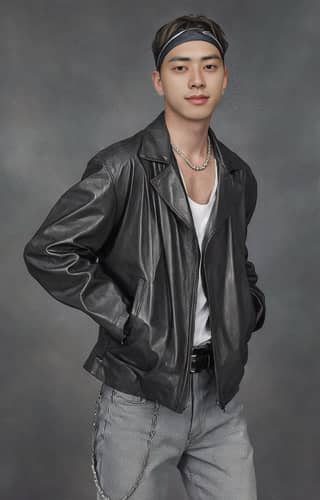 Man in a leather jacket and bandana posing.