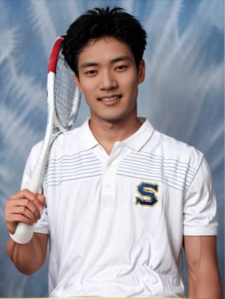 Man smiling while holding a tennis racket.