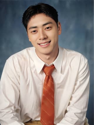 Man wearing a white shirt and orange tie posing.