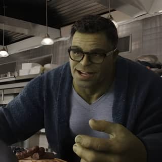 Hulk sedang makan pizza di dapur dengan piring makanan dan laptop dari The Incredible Hulk (2012).