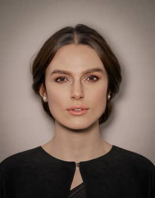 Woman with brown hair wearing a black top and tie.