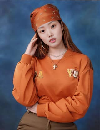 Mujer con sudadera naranja y diadema, posando para una foto.