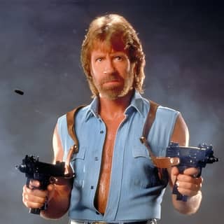 A man wearing a blue shirt and holding two guns.