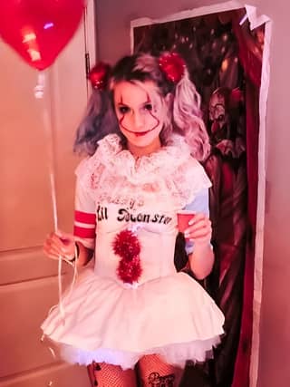 dressed as a clown in a costume from the movie suicide squad holding a balloon and a red heart