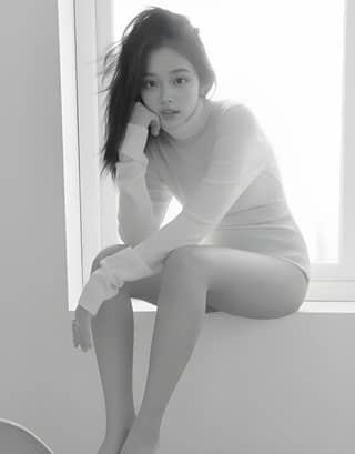Korean model and singer sitting on a window ledge in black and white.