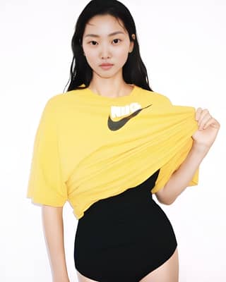Woman wearing a yellow Nike t-shirt and black swimsuit.