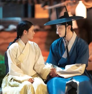 The King and I Korean drama featuring two Asian women sitting on a bench talking.