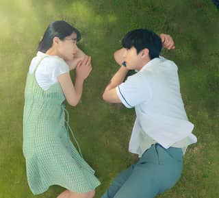 Two women laying on the grass and looking at each other in the secret garden.