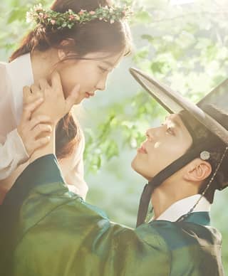 A bride and groom in traditional Korean clothing.