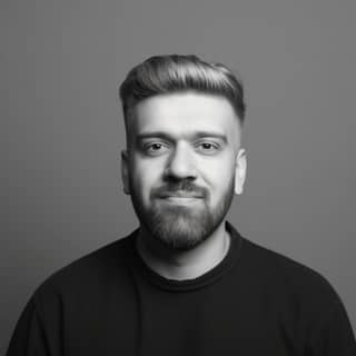 Un hombre con barba y gafas sonriendo a la cámara.