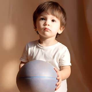 A cute 3-year-old boy with a basketball in his hand Stand in the children's room Light and shadow effect Realistic hair