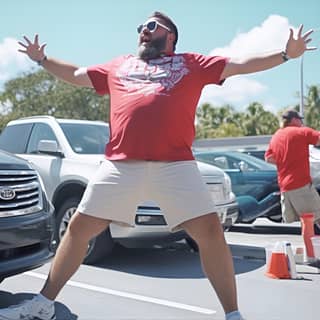 drunken sports fan showing off in Miami parking lot, in a red shirt is jumping in the parking lot