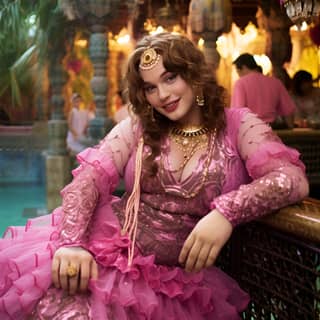 17-year-old chubby male smiles in a delicate Arabian pink lace dress with opened chest big hairdress with thick ligth black