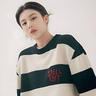 memakai sweater bergaris dengan kata 'spell edit' di atasnya