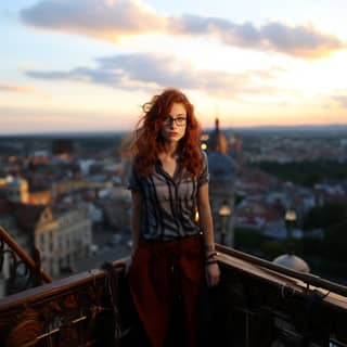 Wunderschöne junge Frau mit roten Haaren und Brille steht auf der Spitze eines Wolkenkratzers zur magischen Stunde mit einem schüchternen Lächeln und intensiv blauen Augen.