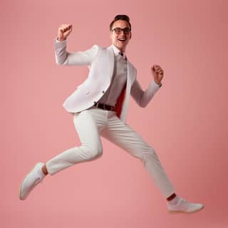 in a white suit and glasses is jumping