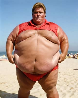 Un hombre gordo en un traje de baño rojo es visto en la playa.