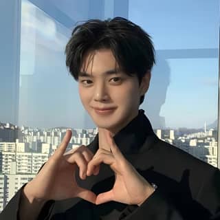 in a suit making a heart with his hands