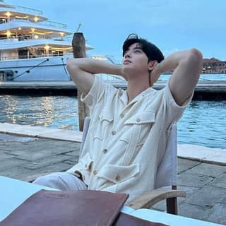 sitting in front of a yacht with his arms up