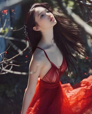 Uma mulher num vestido vermelho posando na floresta.