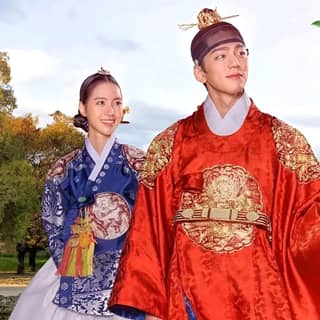 Un couple en tenue traditionnelle coréenne pose pour une photo.