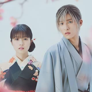 two people in kimono standing next to a tree