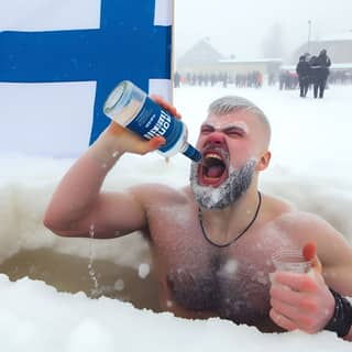 在雪地里喝着一瓶啤酒。