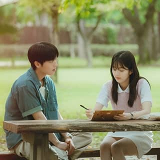 a couple sitting at a picnic table in the park