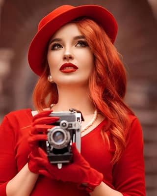 in a red dress holding an old camera