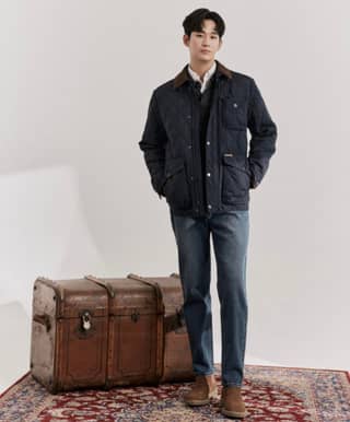 in a blue jacket standing next to a suitcase