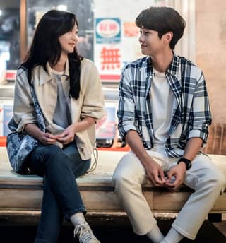 a couple sitting on a bench in front of a restaurant