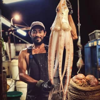 holding up a squid at a market