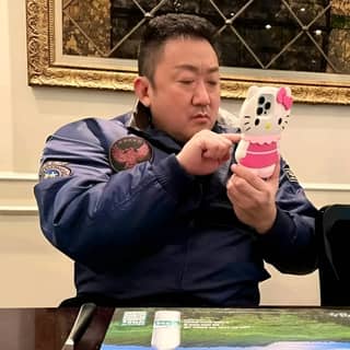 in a blue jacket is holding a hello kitty