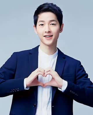 in a suit making a heart shape with his hands